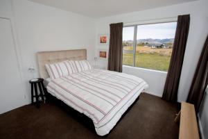 a bedroom with a bed and a large window at House Horse & Hound on Argelins in Hanmer Springs