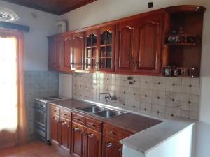 a kitchen with wooden cabinets and a sink at Kokkinos Apartments in Arillas