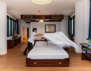 Una mujer está haciendo una cama en una habitación en Hotel Bellavista Club-Caroli Hotels, en Gallipoli