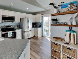 a kitchen with white cabinets and a stainless steel refrigerator at Blue Me A Wave in North Topsail Beach