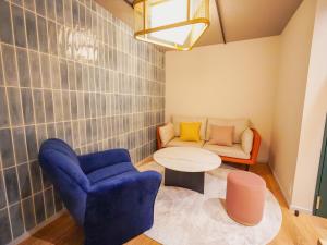 a living room with a blue chair and a couch at The GALA Hotel Umeda in Osaka