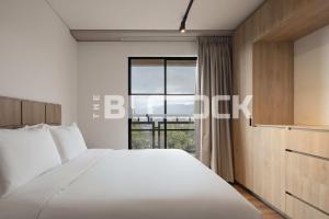 a bedroom with a large white bed and a window at Udara Polo - The Block in Bogotá