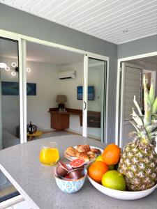 a table with a bowl of fruit on a counter at Le Cocon Miel - Plage, Jardin, Adapté aux Groupes in Folle Anse +20 photos