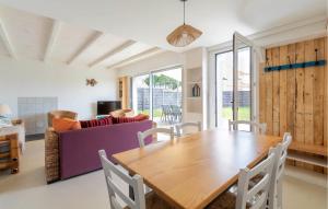 a dining room with a wooden table and a purple couch at Charmante Maison Proche Mer in Notre-Dame-de-Monts