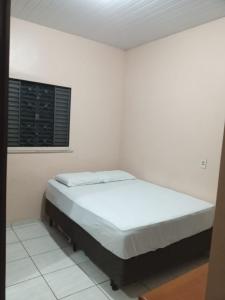 a bed in a white room with a window at Casa in Fortaleza