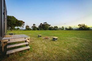 a field with two benches and a fire in the grass at Pyrenees Views by Tiny Away in Avoca