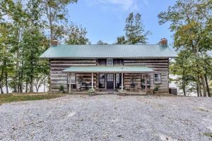 a log cabin with a tin roof on a gravel driveway at Hickory Haven Cozy Lakefront Escape & Dock in Cadiz