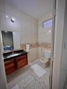 a bathroom with a toilet and a sink and a mirror at Pousada Kalango Flecheiras in Trairi
