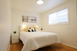 ein weißes Schlafzimmer mit einem Bett und einem Fenster in der Unterkunft Rocky Mtn Escape-3 bdrm-near shops, dining, UofC in Calgary
