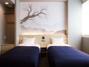 two beds in a room with a painting on the wall at Minn Shijo Omiya in Kyoto