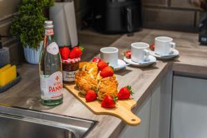 a wooden cutting board with strawberries and a bottle of wine at City Centre Luxury Apartment, Sofa Bed, Netflix, WiFi, Relocators, Contractors, Families Welcome in Leicester