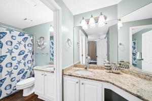 a bathroom with a sink and a toilet and a mirror at Pool & Spa - Beachfront - Golf - King Bed in Gulf Highlands