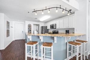 a kitchen with white cabinets and a counter with stools at Pool & Spa - Beachfront - Golf - King Bed in Gulf Highlands