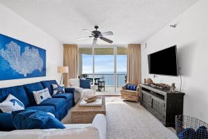 a living room with a blue couch and a flat screen tv at Pool & Spa - Beachfront - Golf - King Bed in Gulf Highlands +29 photos