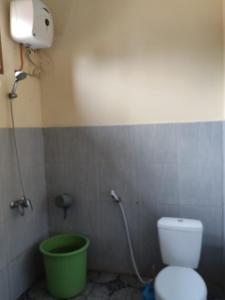 a bathroom with a toilet and a green bucket at Viunya Gaga Homestay in Mantang