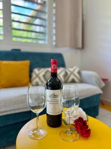 a bottle of wine and two wine glasses on a table at Kataléa - Plage, Piscine, Espace détente in Grand-Bourg