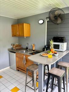 a kitchen with a table with chairs and a microwave at Kataléa - Plage, Piscine, Espace détente in Grand-Bourg