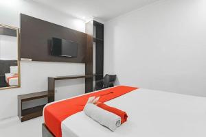 Klandasan-besarHotel Grand Ompo的一间卧室配有一张带红色毯子的床和一台电视。