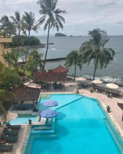 a swimming pool with umbrellas and the ocean at Bali Palms Resort-412 in Candidasa