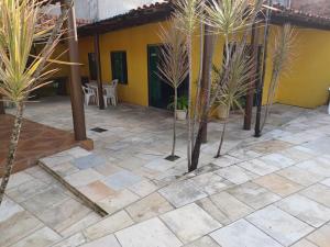 a patio with palm trees in front of a yellow house at Cantinho da paz in Maragogi