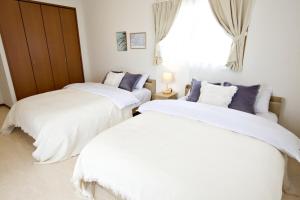 two white beds in a room with a window at Maeda Vacation Style in Onna