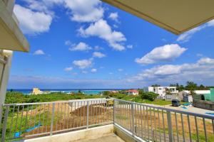 a balcony with a view of the ocean at Maeda Vacation Style in Onna