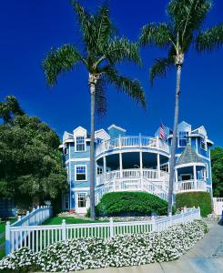 a blue house with palm trees and a white fence at Enchanting Chateau By The Beach - STR15-0330 in Dana Point