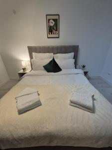 a large white bed with two towels on it at AV Urban Retreat in Ploieşti