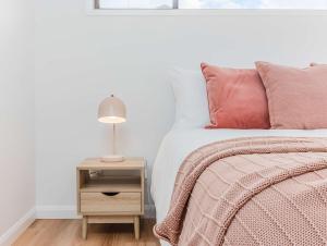 a bedroom with a bed and a night stand with a lamp at Whole House- Pet Friendly Coastal 6 Bedroom in Tweed Heads +65 photos