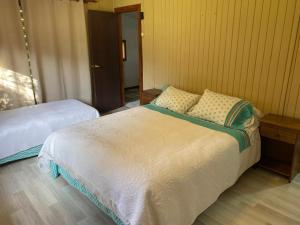 une chambre avec deux lits et un parquet dans l'établissement Cabañita Uriflor, à Los Ángeles