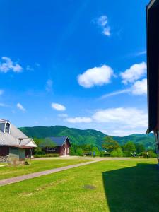 a green field with a house and mountains in the background at Makino MegRia in Takashima