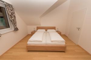 two beds in a room with white walls and wooden floors at Apartment Angerer Bad Aussee in Bad Aussee