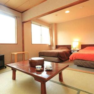 a bedroom with two beds and a coffee table at Hotel SP Haruno in Shinkawa +80 photos