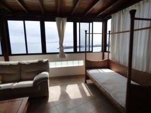 Habitación con cama, sofá y ventanas. en Casa Bonica, en Playa Blanca