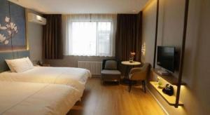 ein Hotelzimmer mit zwei Betten und einem Fernseher in der Unterkunft Magnotel Business Jining Huancheng North Road in Jining