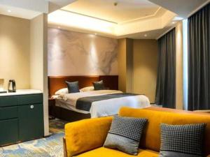 une chambre d'hôtel avec un lit et un canapé jaune dans l'établissement Qingdao Huaxi Hotel Laixi, à Laixi 126 autres photos