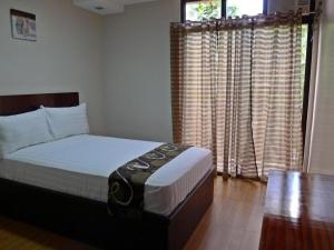 a bedroom with a bed and a window with curtains at Rovic's Tourist Hotel in El Nido