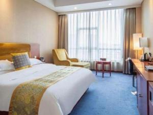 ein Hotelzimmer mit einem großen Bett und einem Schreibtisch in der Unterkunft Qingdao TianRun JinWang Hotel in Qingdao + 168 Fotos