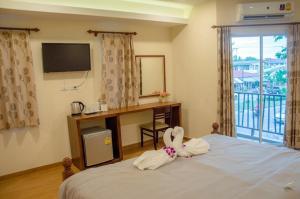 a room with a bed with a desk and a window at The Vintage Residence in Ban Thung Sukla