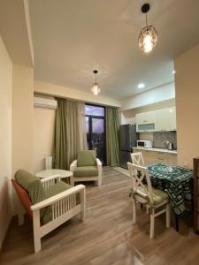a living room with chairs and a table and a kitchen at Avlabari Inn - The coziest place in Tbilisi City