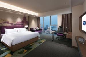 a hotel room with a bed and a desk with a desk at Hampton by Hilton Suzhou XiangCheng in Suzhou