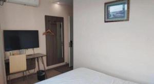 ein Schlafzimmer mit einem Bett und einem Schreibtisch mit einem Fernseher in der Unterkunft 7 Days Inn Tianjin Binhai Passenger Station Huabei Ceramics in Binhai