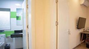 Zimmer mit einem weißen Schrank und einem TV an der Wand in der Unterkunft 7 Days Inn Tianjin Binhai Passenger Station Huabei Ceramics in Binhai