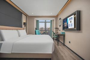 a bedroom with a large white bed and a desk at Xana Hotelle Nanchang Gaoxin Xincheng Wuyue Plaza in Nanchang