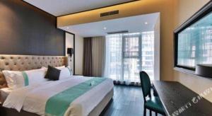 ein Schlafzimmer mit Bett, Schreibtisch und Fenster in der Unterkunft Xana Hotelle Chengdou Xindu Sanhechang Metro Station in Chengdu
