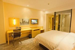 ein Schlafzimmer mit einem Bett, einem Schreibtisch und einem Fernseher in der Unterkunft City Comfort Inn Huizhou Huiyang High-speed Railway Station in Huizhou