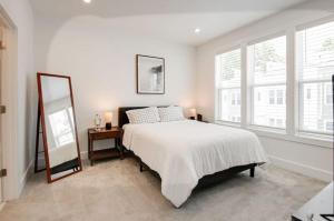 Un dormitorio blanco con una cama y un espejo. en Creative Oasis Minutes to Broadway Rooftop Deck, en Nashville