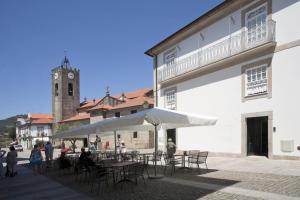 un groupe de tables et de chaises avec une tour d'horloge dans l'établissement Mercearia da Vila, à Ponte de Lima