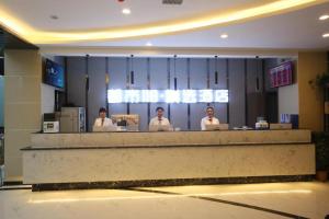 three people sitting at a counter in a lobby at City 118 Selected Hotel Tengzhou Railway Station in Zhaozhuang
