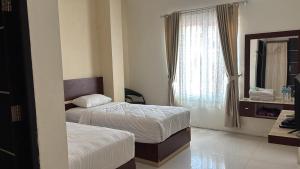 a hotel room with two beds and a window at Hotel Khariz in Bukittinggi